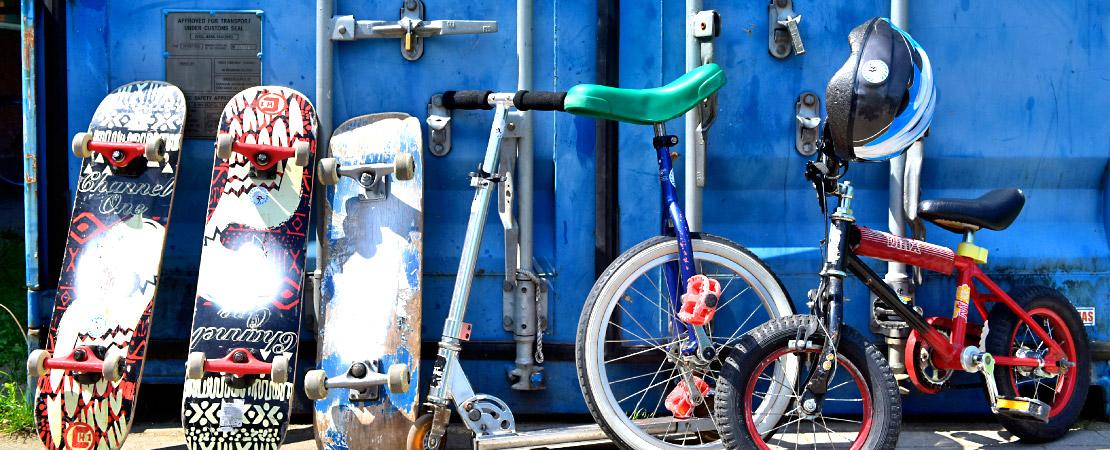 Skateboard und Einräder lehnen an dunkelblauem Container des Sport- und Begegnungsparks Gaarden