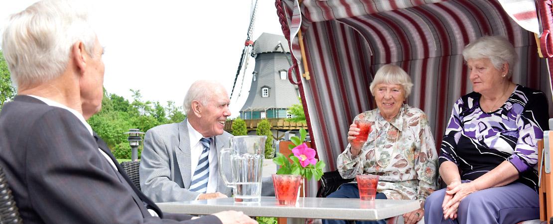 Zwei ältere Damen und zwei ältere Herren sitzen auf der Terrasse des Seniorenstifts