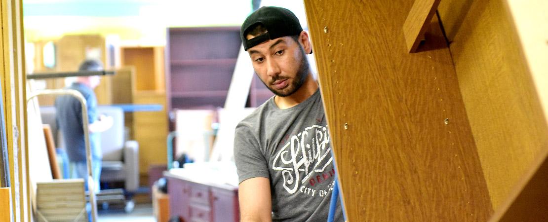 Junger Mann transportiert Schrank